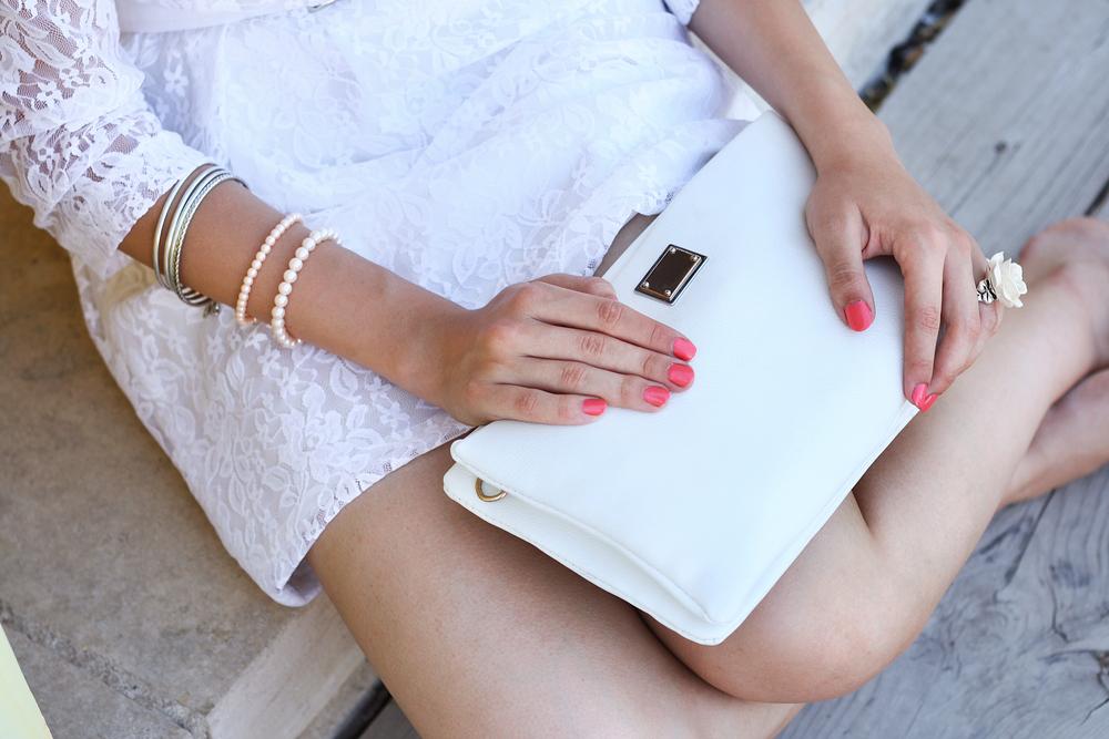 Fashionable woman in a white dress holding her handbag. 