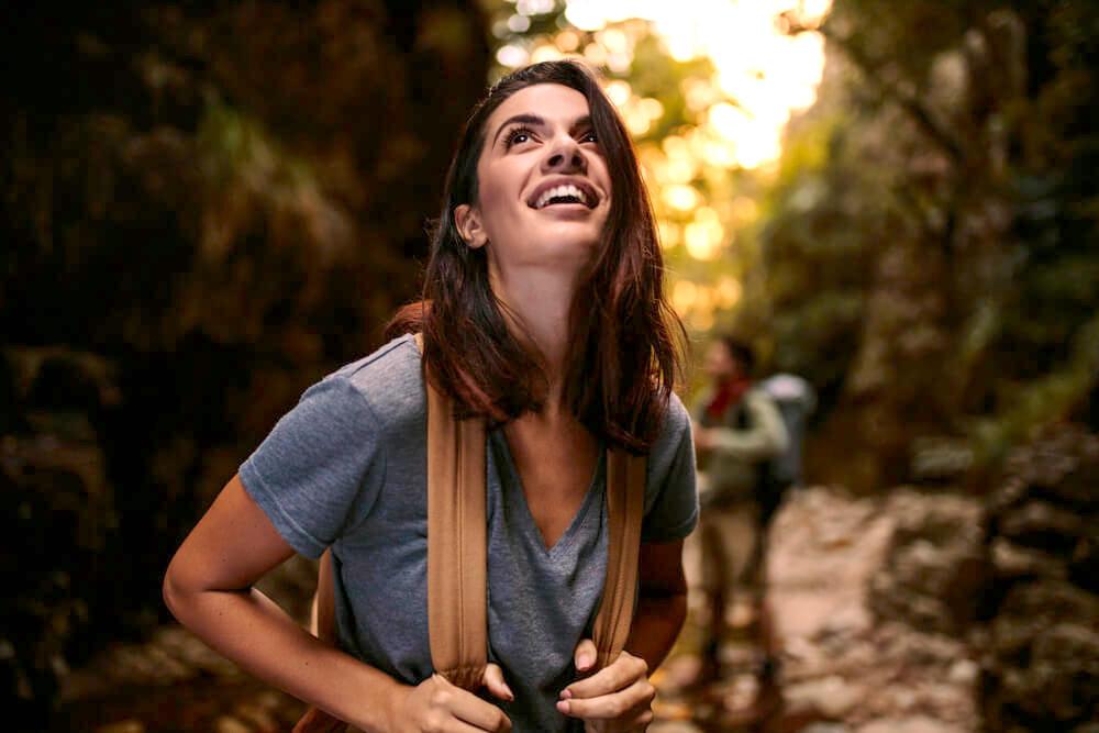Smiling woman with backpack marvelling at her surroundings in nature