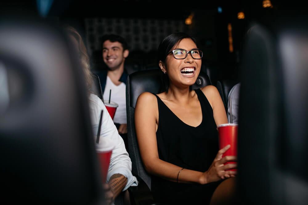 Woman laughing while watching movie in cinema