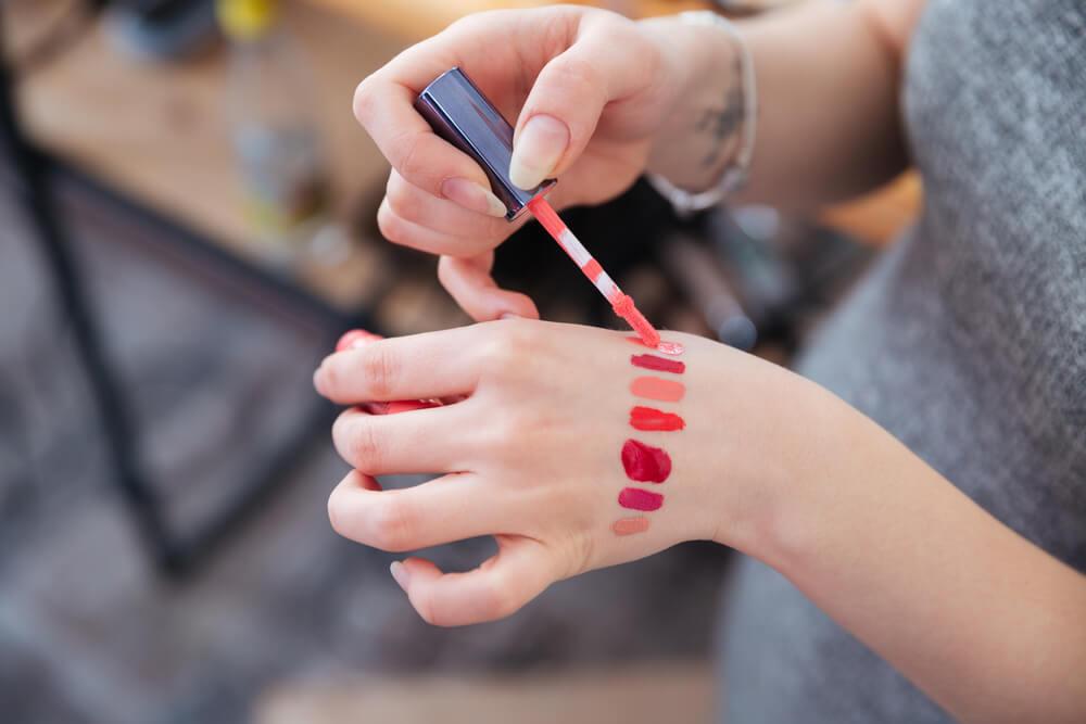Woman testing lipstick on hand