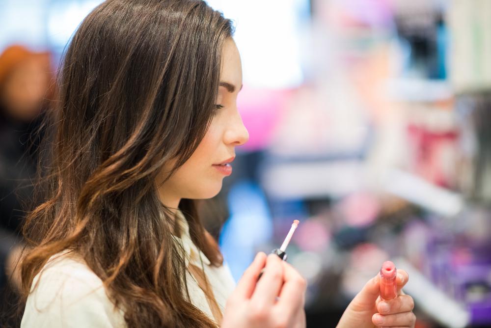 Woman applying a lip stain in a beauty store