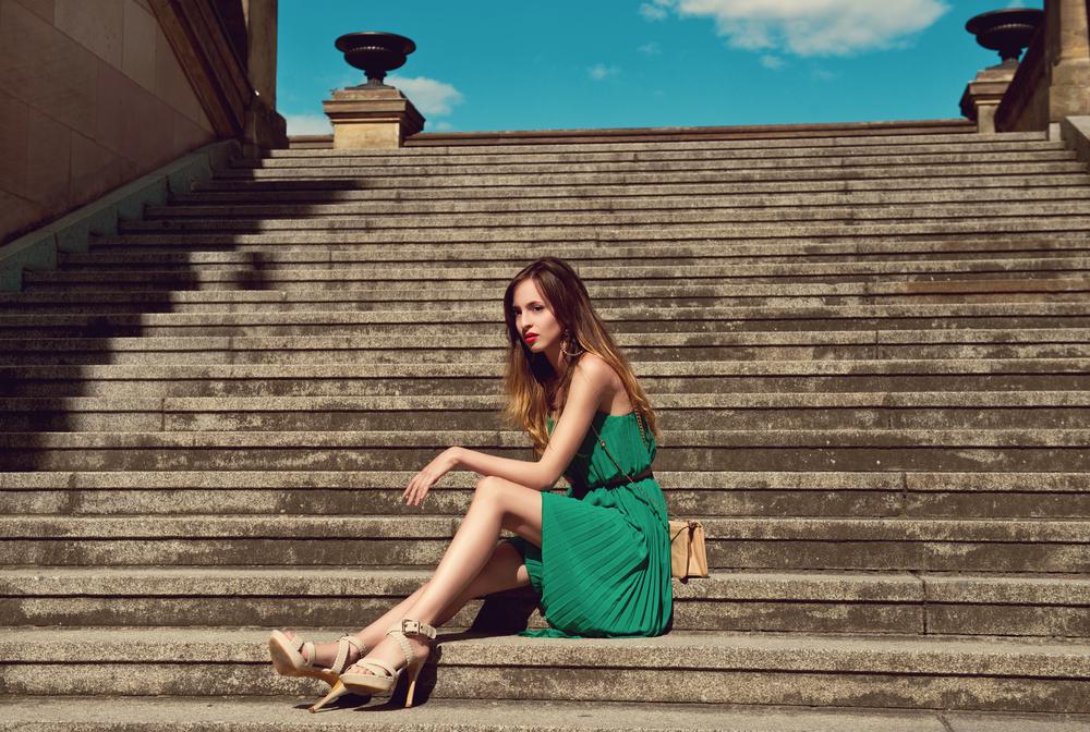 Woman wearing a stylish dress sitting on the stairs.