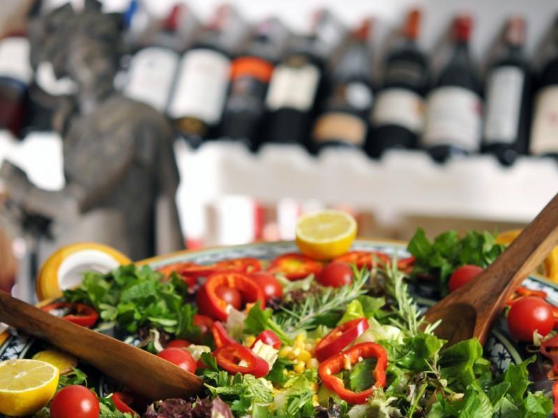Closeup of a salad with wine bottles in the background