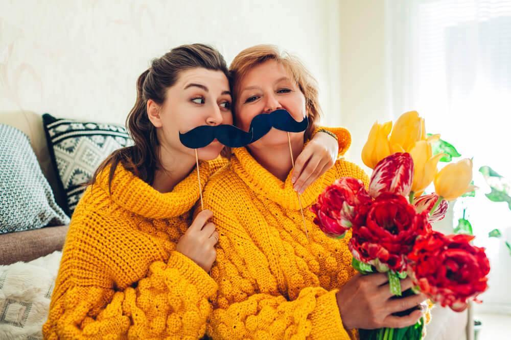 Mother and daughter with fake moustaches being silly and taking selfies 
