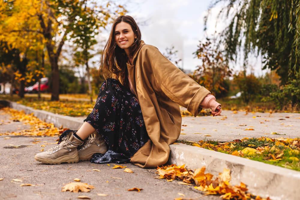 Woman sits on curb wearing maxi dress and jacket