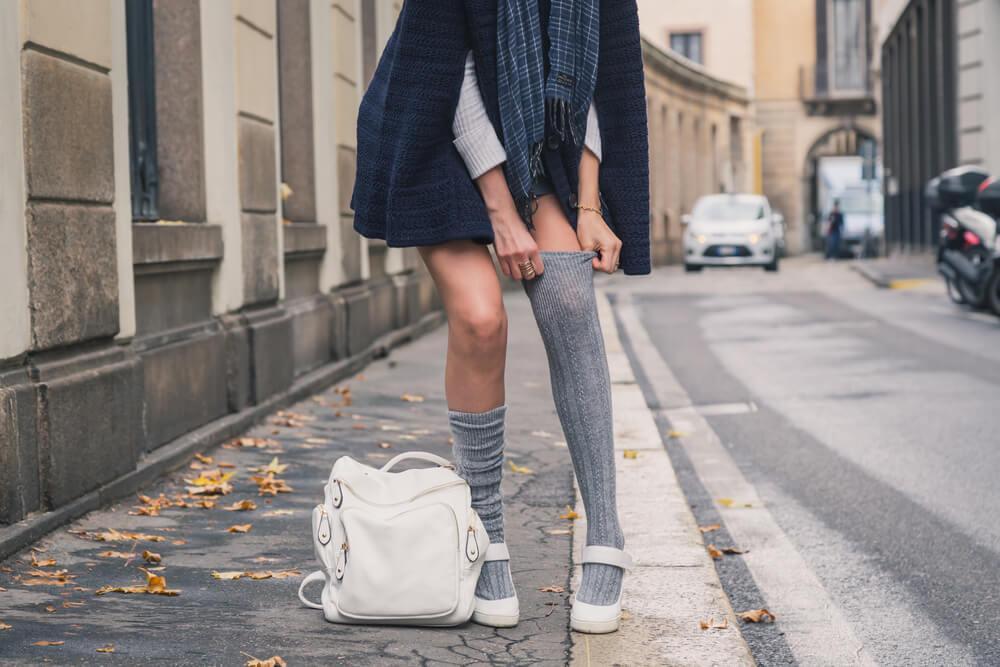 Woman on street pulling up long socks