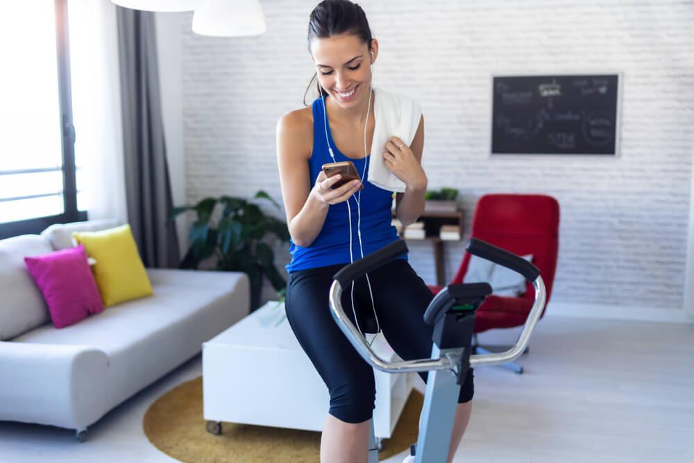 Woman on exercise bike looking at phone