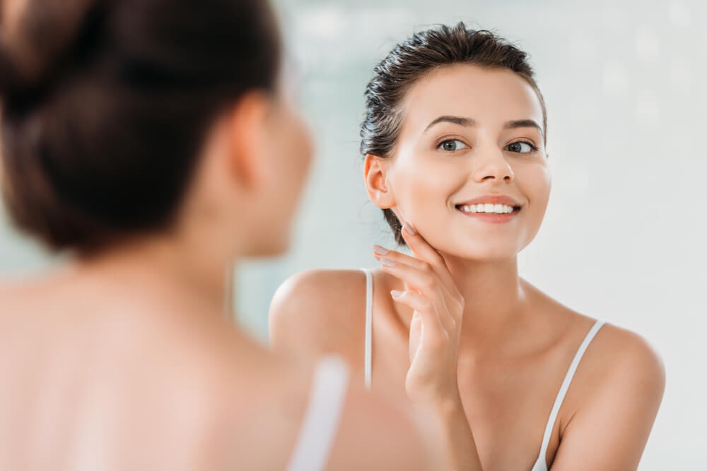 Woman looking at skin in mirror